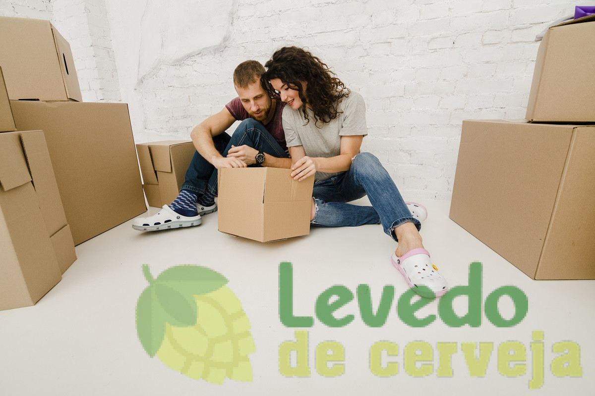Casal no chão olhando dentro da caixa preparados para sua mudança residencial